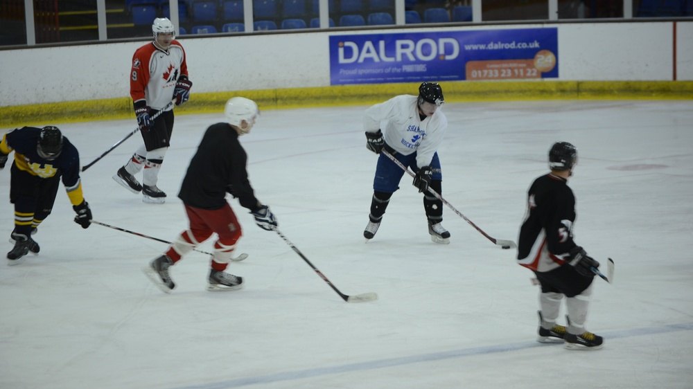 An ice hockey practice or informal game session is taking place at an indoor rink. Five players are visible on the ice, wearing mixed team jerseys and full protective gear including helmets. A sponsor banner for 'DALROD' is visible on the boards in the background.