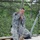 Region 3 Best Warrior Competition A U.S. Army soldier in ACU (Army Combat Uniform) digital camouflage is performing a rope climb exercise on a military obstacle course. The soldier is gripping a thick knotted rope while standing on a wooden platform, appearing to prepare for or demonstrate the climb. Blue safety mats are visible below, and a cargo net structure forms the backdrop.