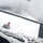 Region 3 Best Warrior Competition An aerial/elevated view looking down at a military soldier in camouflage uniform standing near or on a large white-tarp-covered vehicle or cargo container. Thick rope rigging is visible in the foreground, suggesting the photo was taken from an elevated structure or vehicle. Additional military personnel are visible in the background on what appears to be a wet or snow-dusted surface.