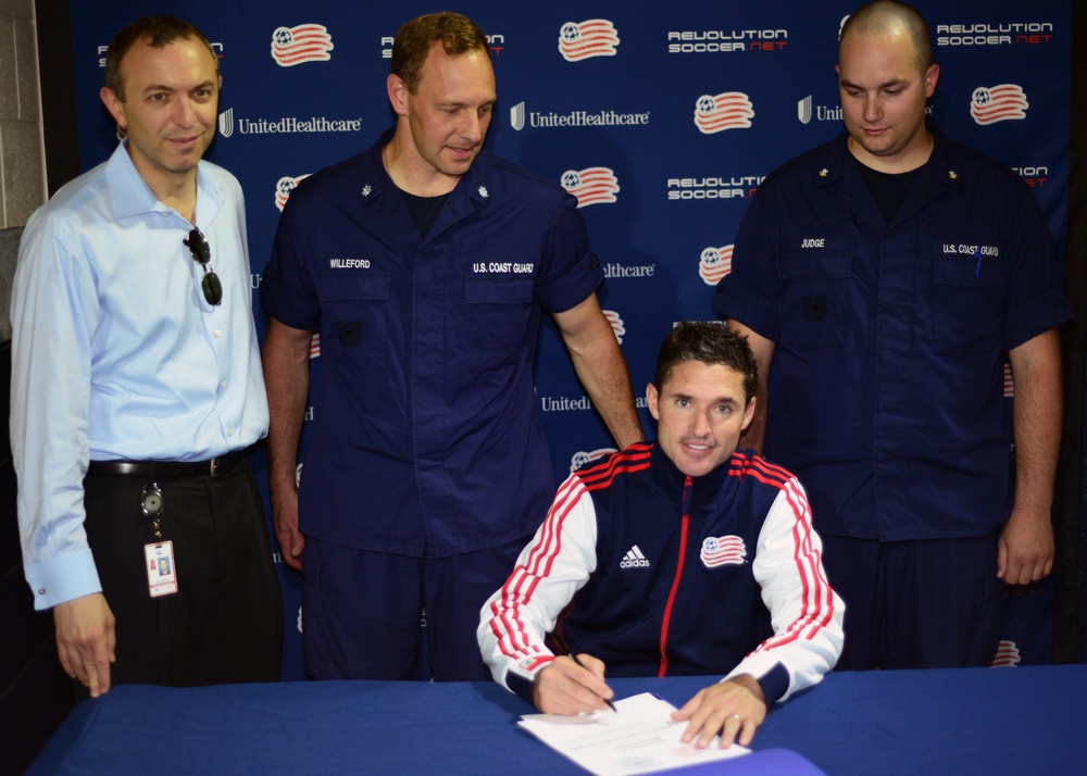 Revolution's coach Jay Heaps signs a document of support with the U.S. Coast Guard