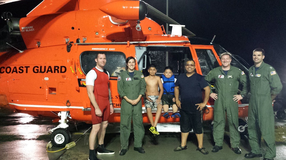 Coast Guard rescue crew stops to take a photo with a family they just rescued