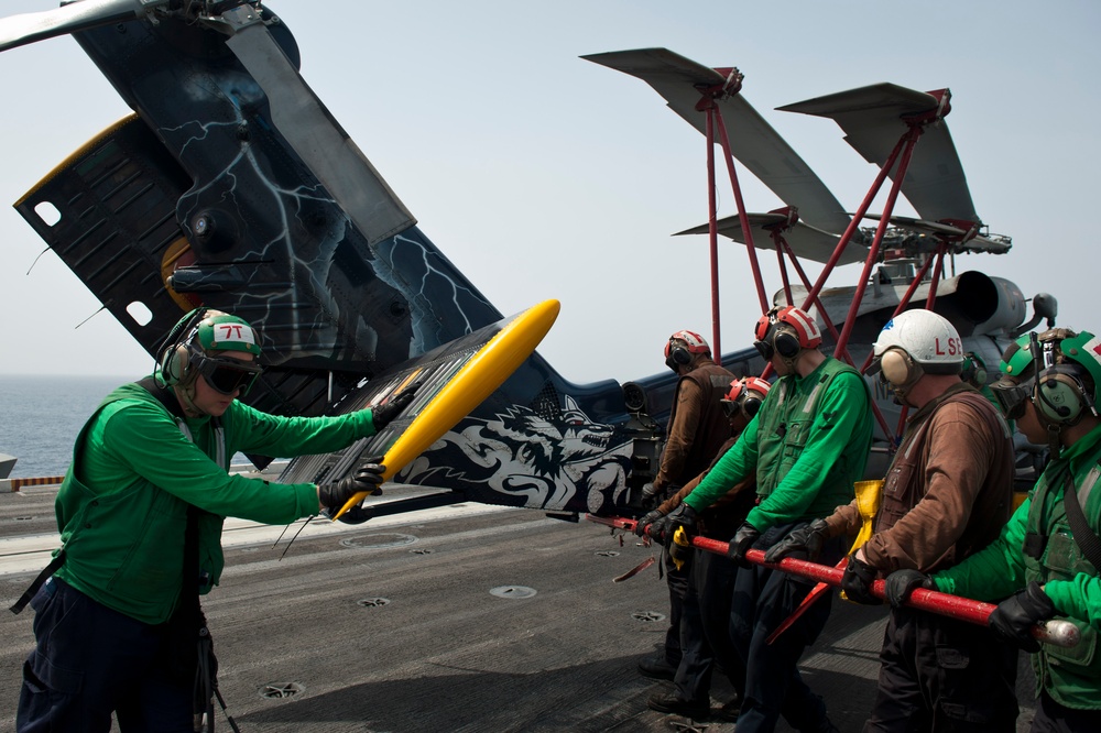 Sailors extend tail of MH-60R Sea Hawk helicopter