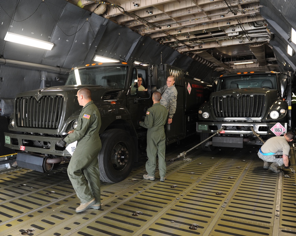 Airmen load refueling trucks onto aircraft