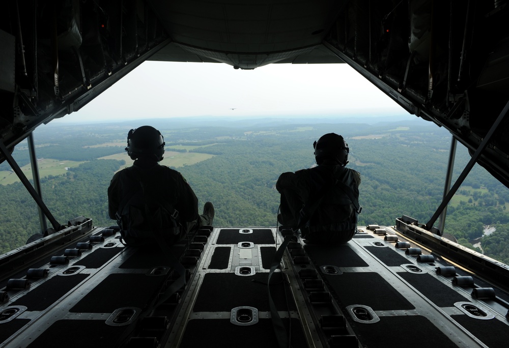 Airmen sit on the cargo door of a C-130J