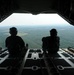 Airmen sit on the cargo door of a C-130J