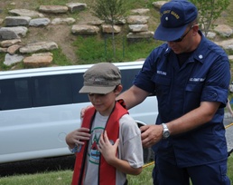 Coast Guardsman shows Cub Scout how to properly wear life jacket