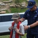 Coast Guardsman shows Cub Scout how to properly wear life jacket