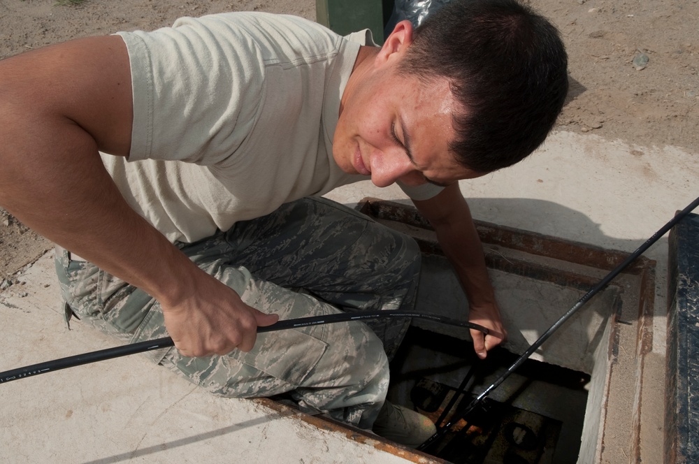 Airmen feed cable under flightline for new tower