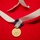 Lt. Gen. Dana Kyle Chipman retirement ceremony A gold military or civilian medal is displayed on a red fabric background. The medal features an embossed shield and wreath design and is attached to a purple and white striped grosgrain ribbon. A longer white satin ribbon is also present, looping behind the medal.