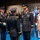 Lt. Gen. Dana Kyle Chipman retirement ceremony A formal U.S. Army military ceremony is taking place in a large indoor venue. Senior officers in dress uniforms are engaged in what appears to be a retirement or change of command ceremony, with a folded American flag being presented. A civilian woman wearing a white lace dress and a medal stands alongside the officers.