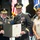 Lt. Gen. Dana Kyle Chipman retirement ceremony A U.S. Army retirement ceremony is taking place, with two senior officers in dress uniforms holding a Certificate of Retirement for Lieutenant General Dana K. Chipman of the United States Army. A woman, likely a family member, stands to the right wearing a medal or medallion. Multiple military flags and a color guard are visible in the background.