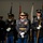 Lt. Gen. Dana Kyle Chipman retirement ceremony A formal U.S. Army military ceremony featuring uniformed soldiers in dress blues standing at attention. The central figure appears to be a senior officer wearing a distinctive ceremonial uniform with a gold belt, aiguillette, and multiple medals. Soldiers in the background carry rifles and flags, suggesting this is an official honor guard or parade formation.
