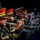 Lt. Gen. Dana Kyle Chipman retirement ceremony A military band performs in formation, with multiple musicians playing trumpets while wearing formal dress uniforms. The musicians are dressed in dark navy/black uniforms with gold trim and distinctive red-topped ceremonial caps. The image is captured from a side angle, creating a dramatic depth-of-field effect against a dark background.
