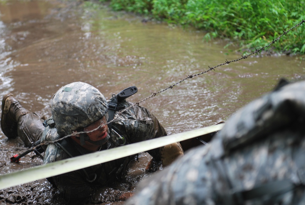 OSW soldier low crawls through the mud and under barbed wire