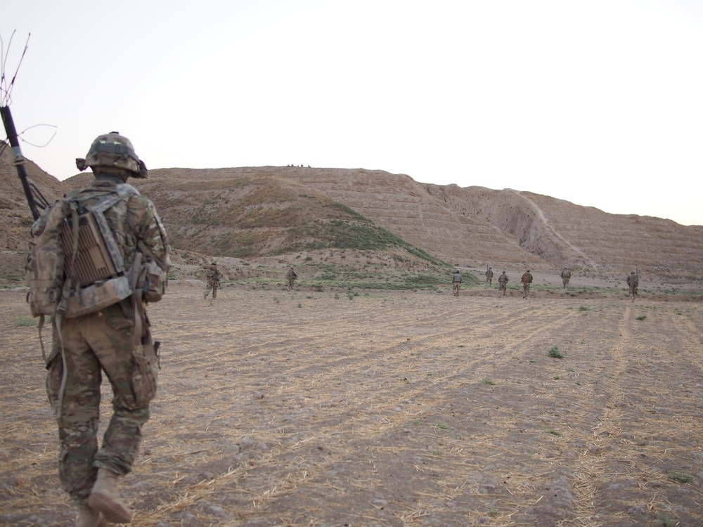 Alpha Section, 3rd Platoon, Apache Troop, 6-4 CAV, crosses a field while a machine gun team provides overwatch from a ridge