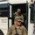 81st Civil Affairs Battalion welcome home ceremony Two U.S. Army soldiers in MultiCam (OCP) camouflage uniforms are exiting or standing near a white Blue Bird All American bus. The foreground soldier, identified by name tape as 'Rodriguez,' wears captain rank insignia (two bars) and an ISAF patch, and is carrying an M4 carbine. Both soldiers are in full combat gear with tactical vests and backpacks.