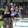 81st Civil Affairs Battalion welcome home ceremony A group of women and children are walking out of what appears to be a military building, with at least one uniformed soldier visible in the background. Several people are carrying signs, including one that reads 'We Are So Proud of You Welcome Home,' suggesting this is a military homecoming or welcome-back event. The mood appears celebratory, with people smiling and dressed in casual attire.