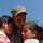 81st Civil Affairs Battalion welcome home ceremony A soldier in U.S. Army camouflage uniform and patrol cap embraces two children in an emotional moment, kissing one on the forehead. The name tape on the uniform reads 'SOSTRE.' The scene appears to be a military homecoming or farewell, set against a clear blue sky.