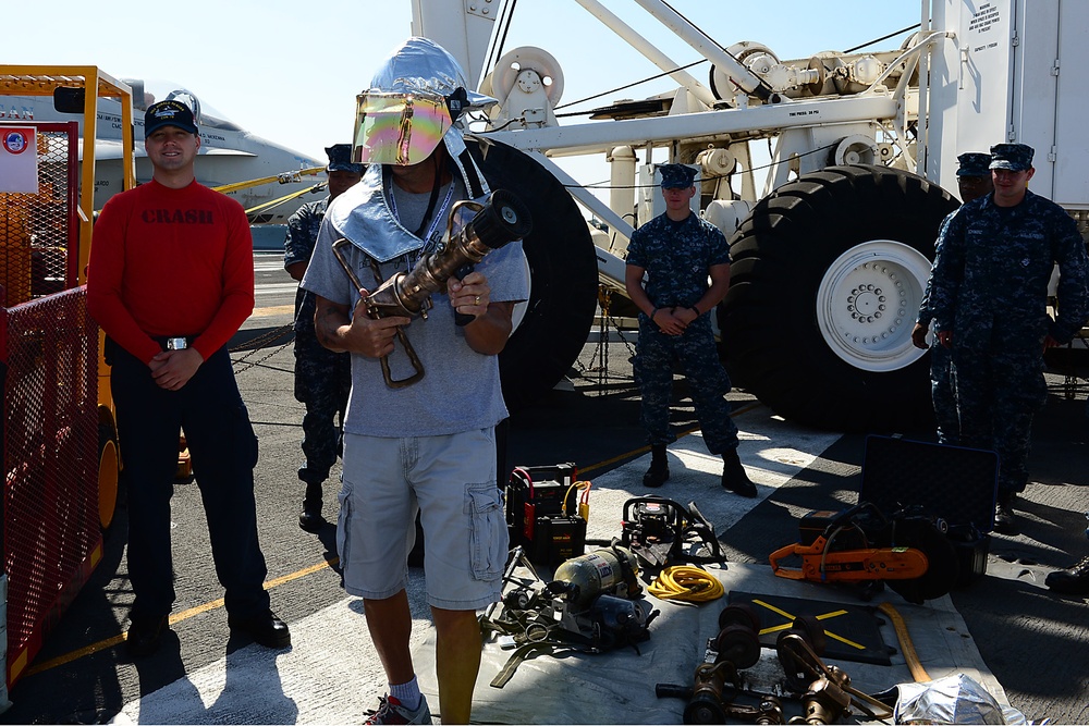 A guest touring the aircraft carrier USS Ronald Reagan (CVN 76) dons part of a firefighting ensemble