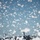 Flurry of foam released at Travis Military transport aircraft are parked on a flight line or tarmac, partially obscured by large quantities of white foam or snow-like material in the foreground and airborne throughout the frame. The white substance appears to be firefighting foam or artificial snow dispersed across the area. At least two large military cargo aircraft are visible in the background against a clear blue sky.