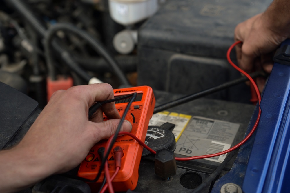 Vehicle maintenance technician uses a multimeter to check the voltage on a alternator 