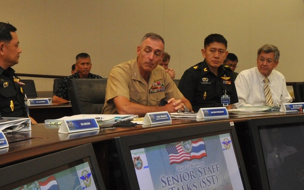 A formal military meeting between U.S. and Thai military officials, identified as 'U.S.-Thailand Senior Staff Talks (SST).' Participants are seated at a conference table with name placards, and multiple monitors in the foreground display the SST title slide featuring both the American and Thai flags. The setting appears to be an official military conference room.