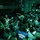 A large group of civilians are packed tightly inside the cargo hold of a military transport aircraft, illuminated by green ambient lighting. The scene appears to depict a mass evacuation or humanitarian airlift operation, with people sitting and lying on the floor in extremely crowded conditions. At least one person is wearing a shirt marked 'Engineering Office,' suggesting these may be civilian workers or disaster survivors being transported.
