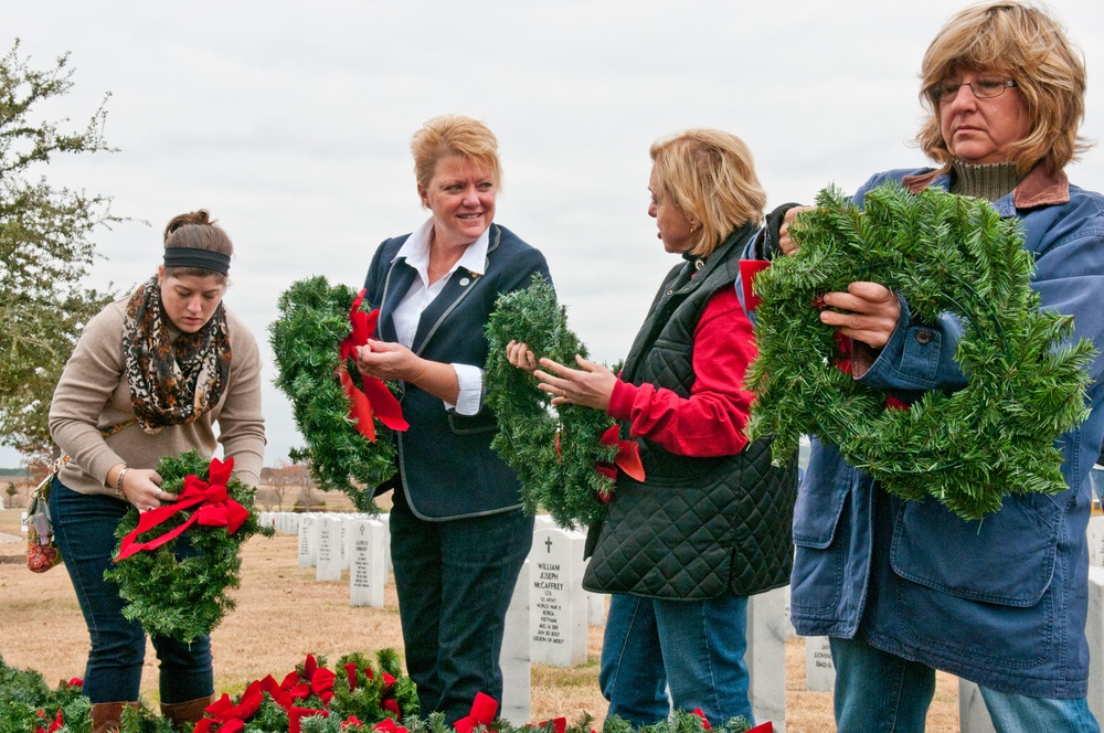 Volunteers place Christmas wreaths at veterans cemetery