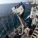 Sailors perform maintenance on the starboard davit