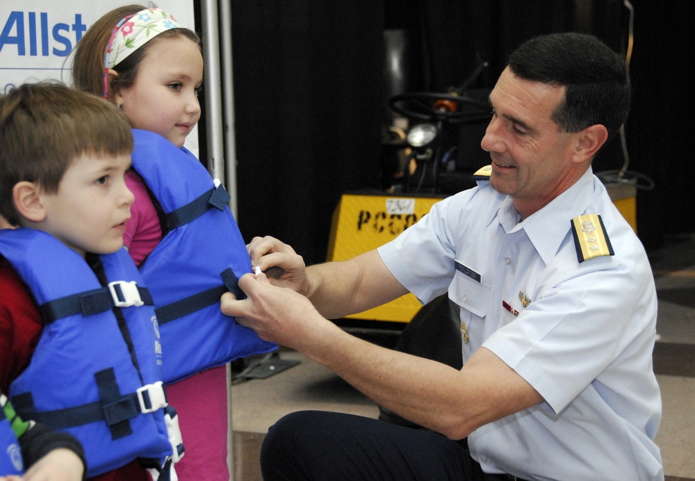 Rear Adm. David Pekoske, Coast Guard Assistant Commandant for Operations, fastens a life jacket around Jillian DeBenedetto (For