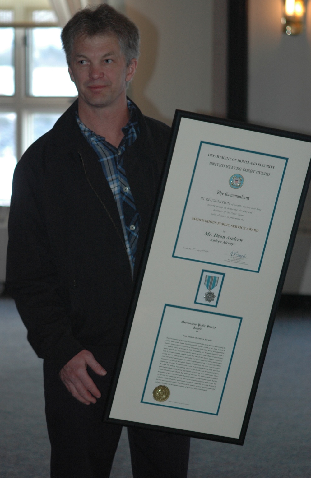 Dean Andrews holding the Coast Guard Meritorious Public Service Award