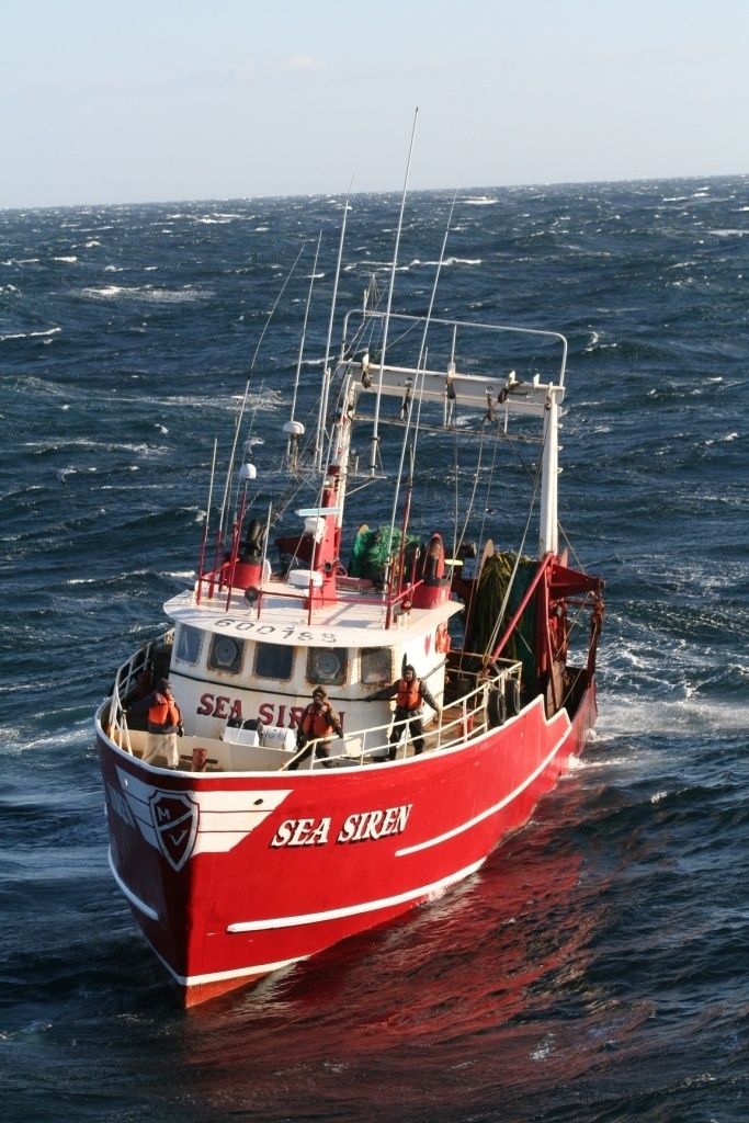 Disabled fishing boat crew prepares to receive tow line from Coast Guard cutter crew