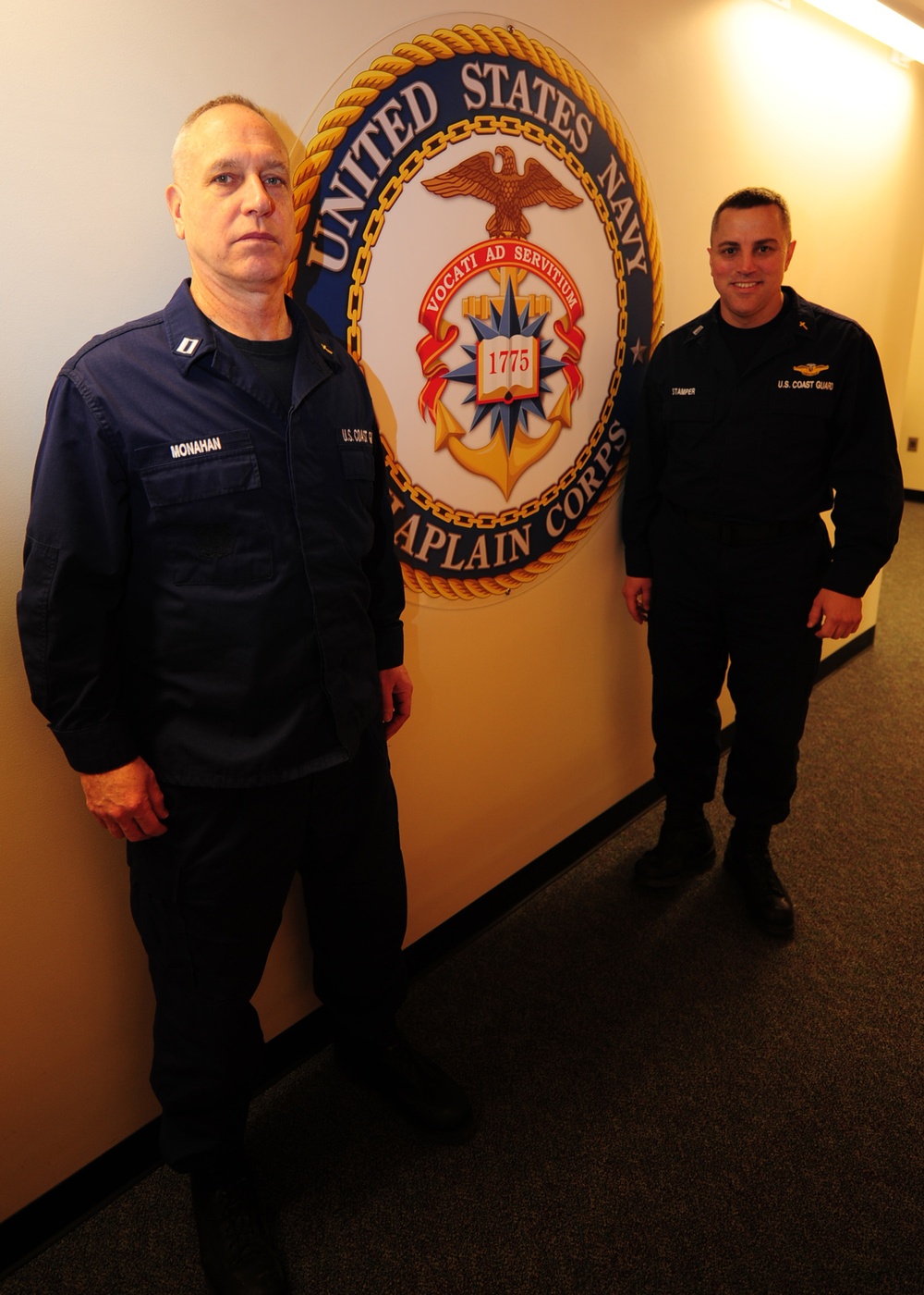 Kodiak-based Coast Guard chaplains stand in front of Navy Chaplain Corps seal