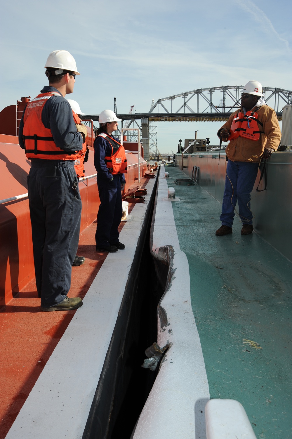 Marine safety inspectors discuss repair plans for a damaged barge