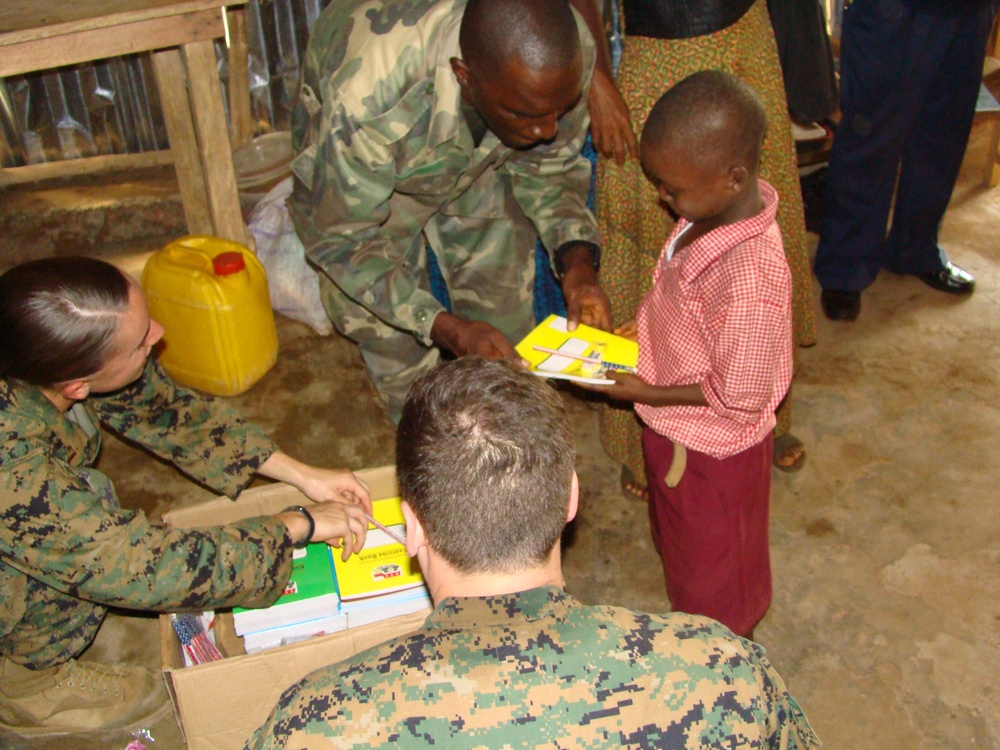 Marines and RSLAF members handing out donated school supplies.