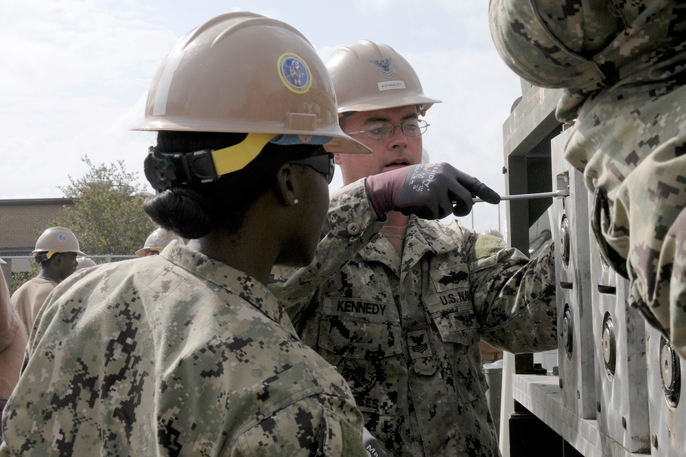 Seabees assigned to NMCB 11 set up and calibrate an Automatic Building Machine.