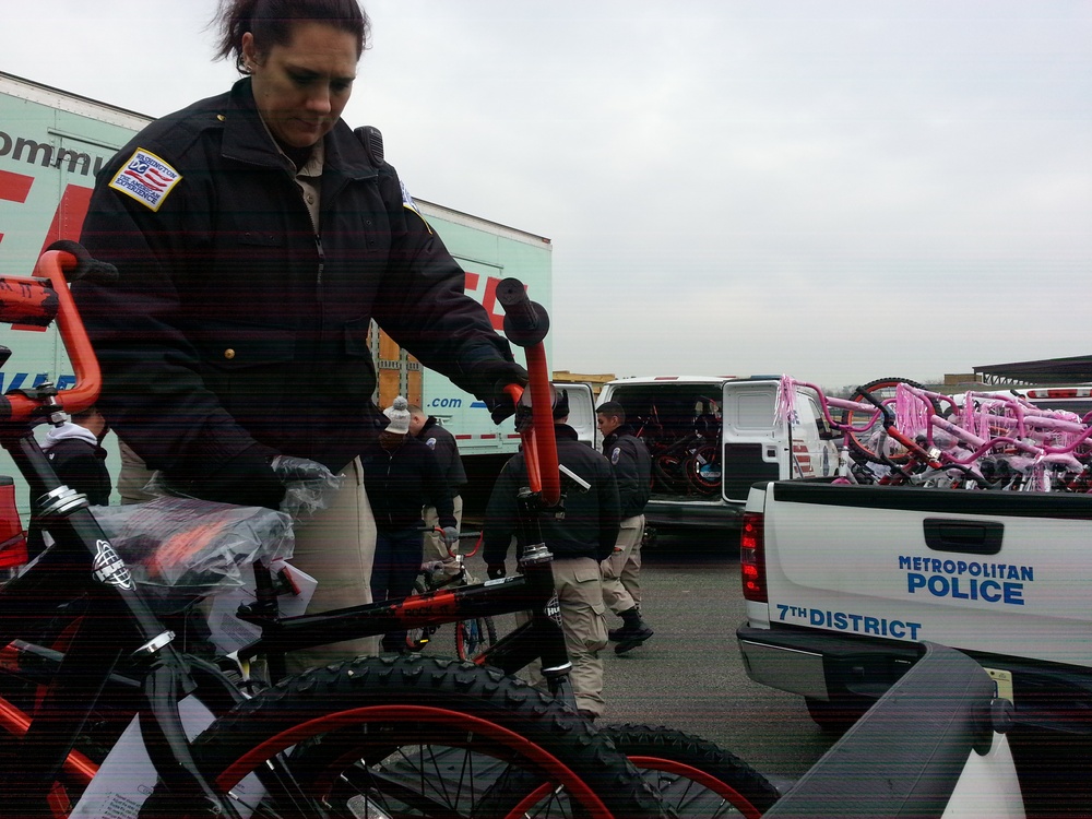 Cadet from the Metropolitan Police Department Academy loads a bicycle, one of many donated to the Toys for Tots program