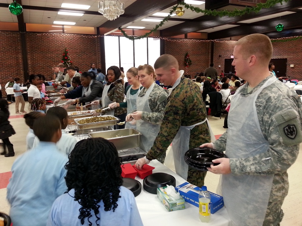 Military members serve food to youth