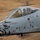 A close-up aerial photograph of a U.S. Air Force A-10 Thunderbolt II (Warthog) attack aircraft in flight, bearing tail number 188. The aircraft features a distinctive aggressive owl/bird nose art and is assigned to COL. MARK ANDERSON and TSGT. ORION STELL as indicated by the stenciled names on the fuselage. A pilot in full flight gear is visible in the cockpit.