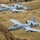Two A-10 Thunderbolt II (Warthog) aircraft flying in formation over rural terrain. Both aircraft bear Arkansas Air National Guard markings with 'FS' tail codes and 'ARKANSAS' text on the vertical stabilizers. The foreground aircraft displays nose art and is marked 'City of Fort Smith.'