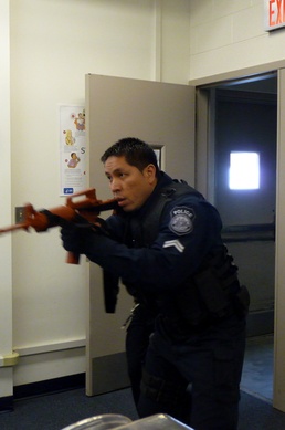 A DOD police officer at Joint Base Anacostia-Bolling rushes through a door