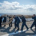 Sailors move a mooring line across the flight deck