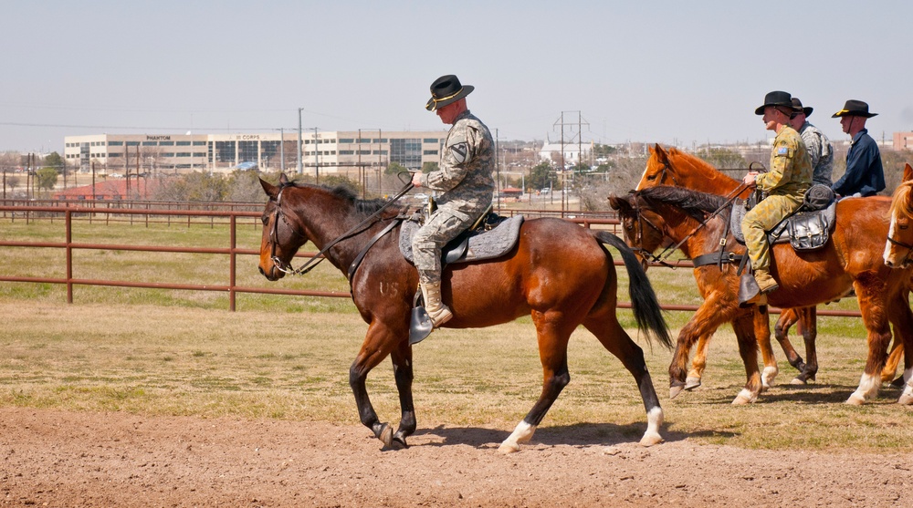 Brig. Gen. Michael Bills rides a horse past III Corps building