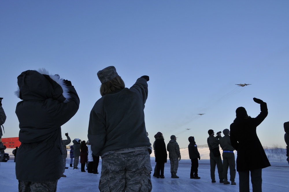 Members watch as aircraft fly over base