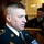 A U.S. Army soldier in dress uniform is being interviewed by WMUR, a New Hampshire television news station. He is speaking into a microphone in what appears to be an indoor formal setting. A second uniformed military personnel member is visible in the background near a podium.