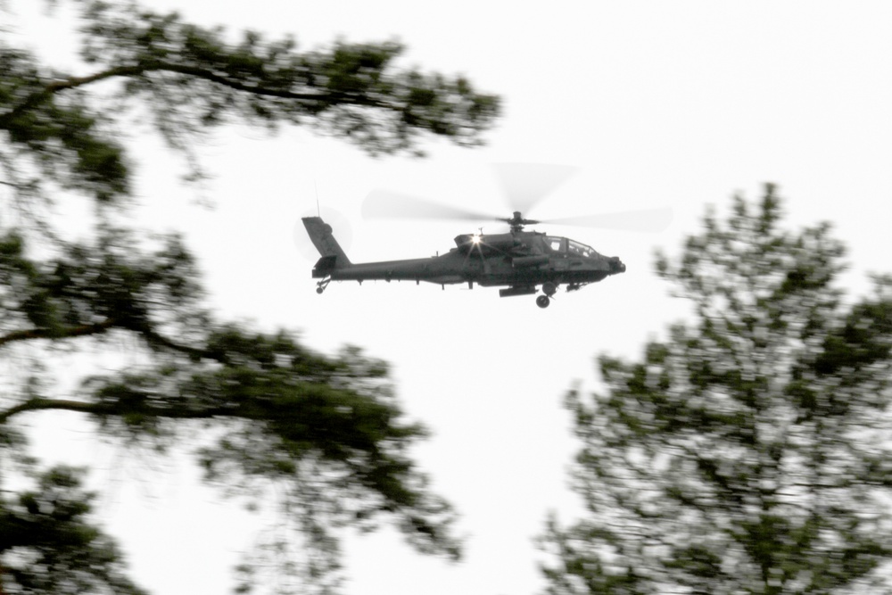 U.S. Army AH-64 Apache flies low above the tree line to support soldiers