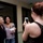 Two women are posing together for a photo while a third woman photographs them with a smartphone. The woman in the center is holding a book titled 'Confessions of a Military Wife' by Mollie Gross. The setting appears to be an indoor hallway or lobby, suggesting a book signing or author event.