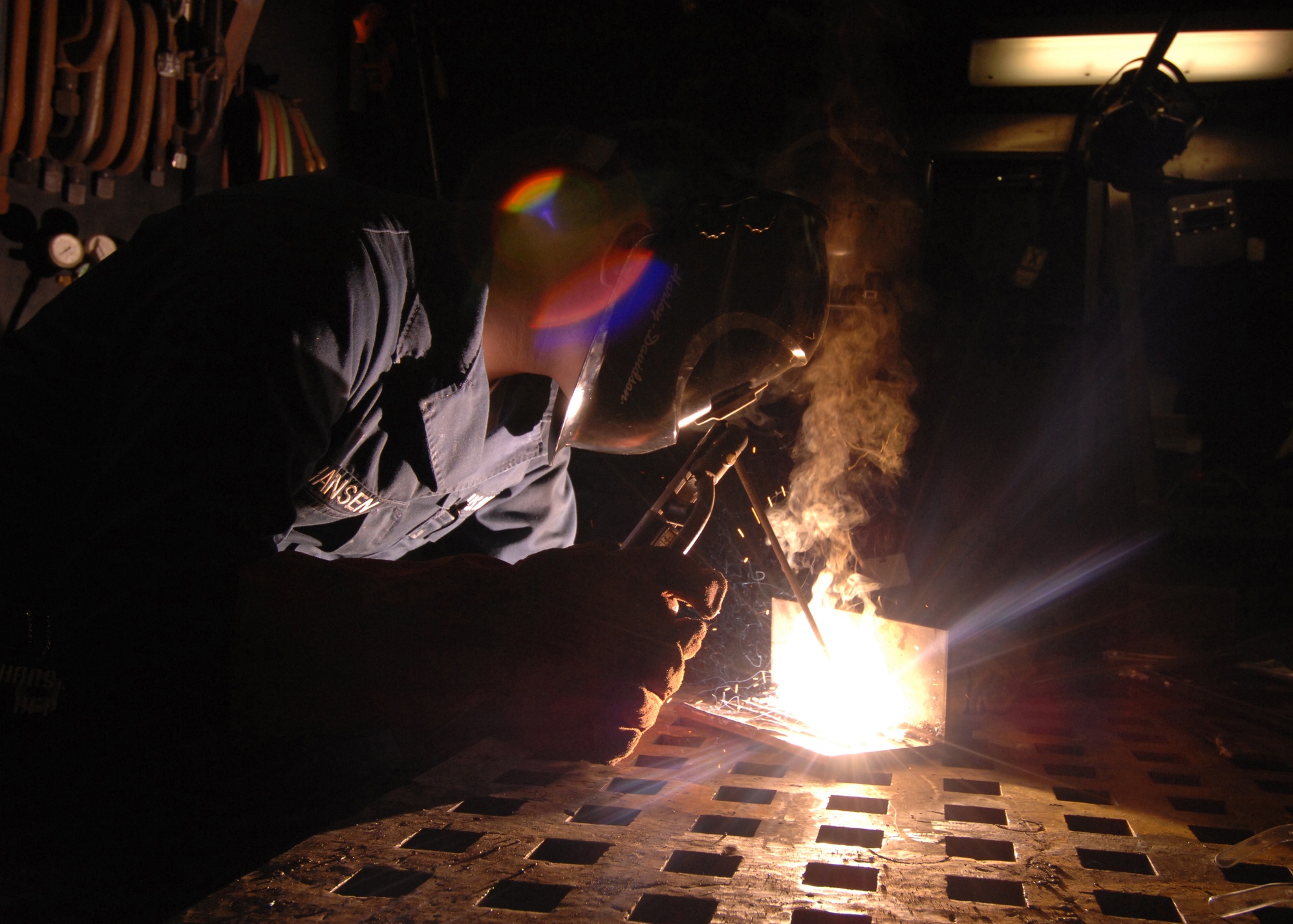 Welder performing a qualification weld as fumes rise from the molten pool