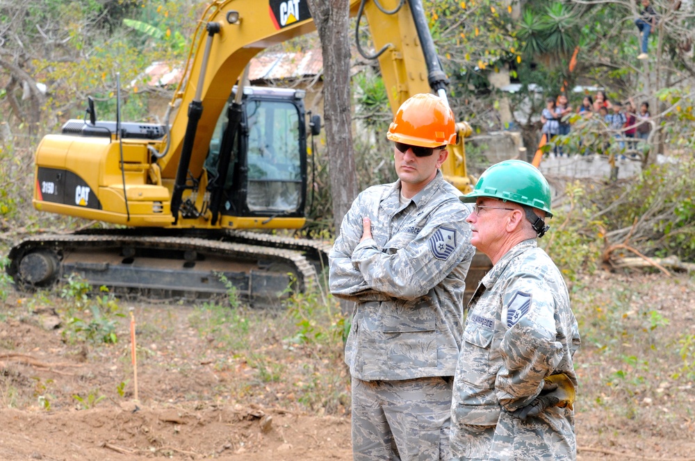 Guatemalan children watch from a nearby tree as Master Sgt. Larry Ricketts discusses construction with First Sgt. Joshua Rich during Beyond the Horizon 2014 on April 8