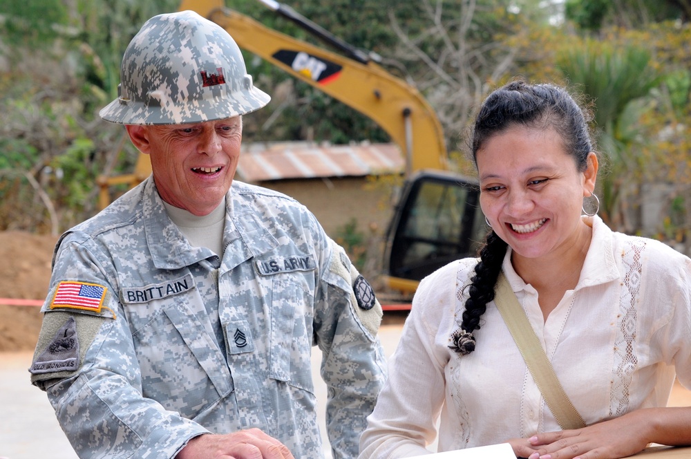 Susana Evangelina Paiz Gonzalez, the school director, smiles after Sgt. 1st Class Timothy Brittain, an engineer with the 35th Engineer Brigade, Missouri Army National Guard informs her that the new school will be finished by the end of June 2014